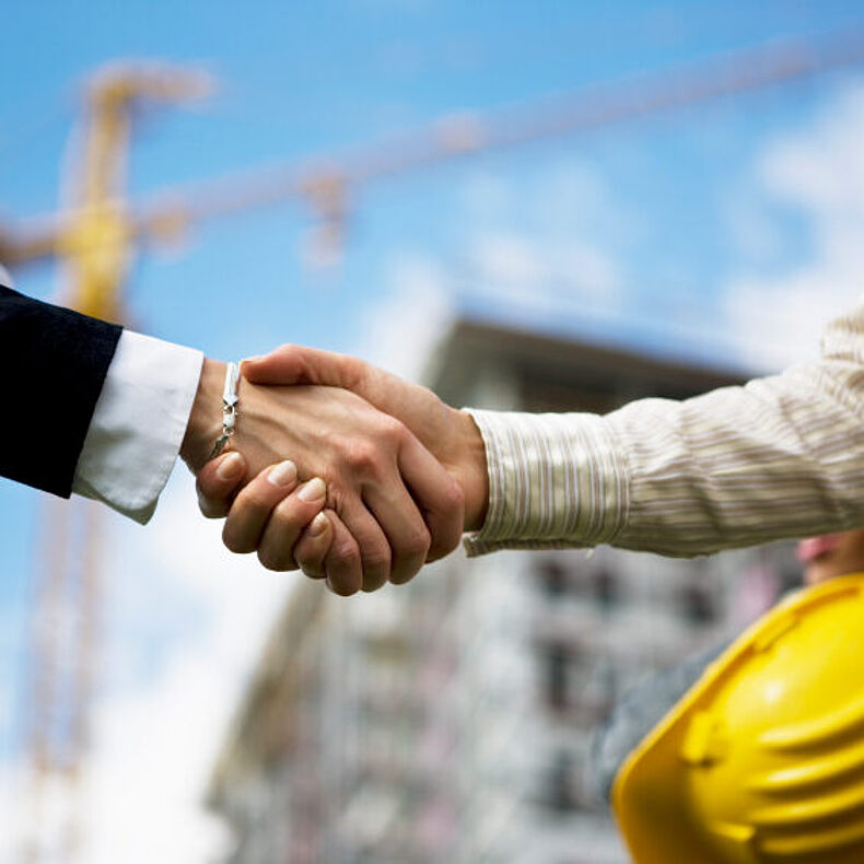 Handshake zwischen Investor und Bauleiter auf einer Großbaustelle
