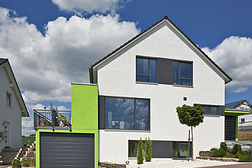 Frontalansicht modernes Einfamilienhaus mit Garage, Balkon und grünen Farbakzenten