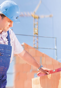 Zwei Handwerker mauern ein Massivhaus und prüfen Ihre fachgerechte Arbeit