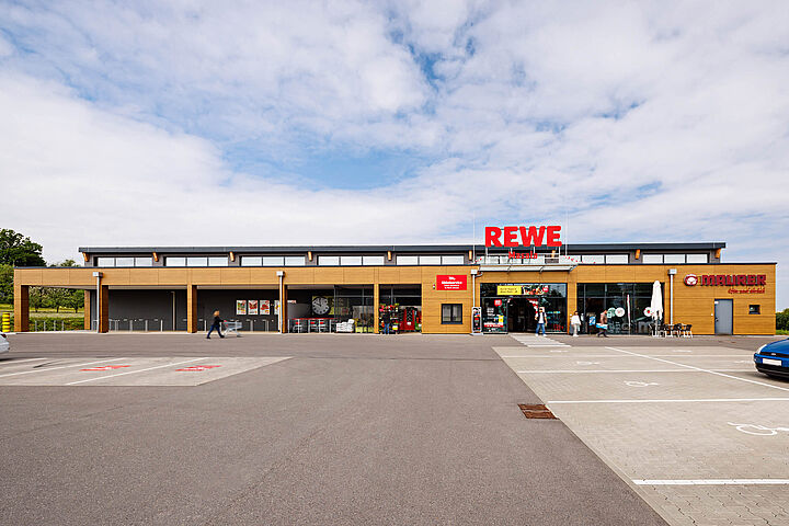 Außenansicht REWE Lebensmittelmarkt mit Parkfläche