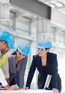 Bauleiter einer industriellen Großbaustelle im Beratungsgespräch über einem Bauplan