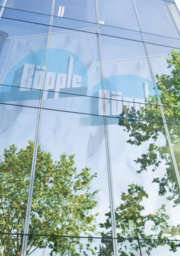 Glasfassade eines modernen Bürgebäude in der sich Unternehmensfahnen von Böpple spiegeln
